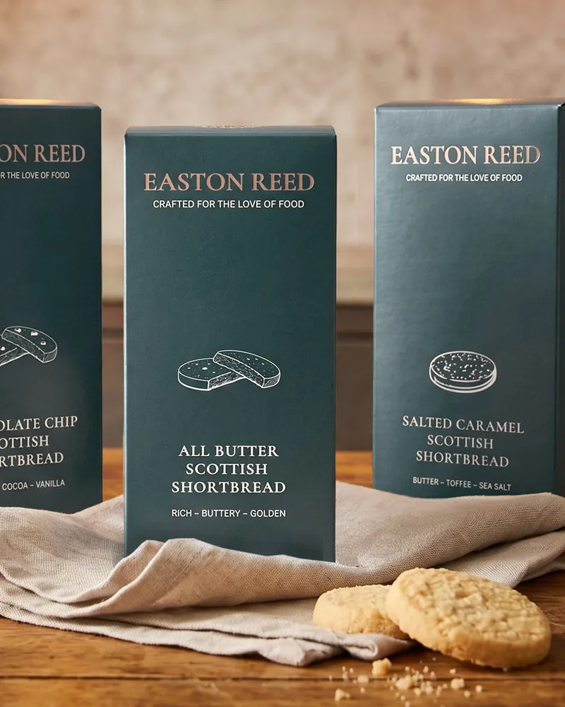 Three Easton Reed Scottish Shortbread boxes on a linen cloth with biscuits